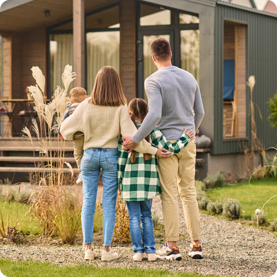 back view family hugging admiring their house